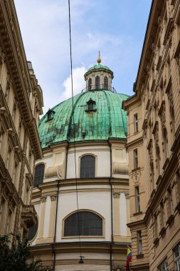 Viyana, Avusturya - 10. Temmuz 2025: Peterskirche 'nin yeşil kubbesinin etkileyici manzarası, Viyana' daki Innere Stadt 'ın geleneksel binalarının arasına yerleştirilmiş bir barok mücevheri