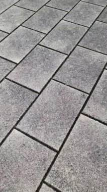 Dönen gri kaldırım taşları dinamik geometrik desen oluşturur, karmaşık yüzey dokusunu ve mimari tasarımı çoklu açılardan ortaya çıkarır.