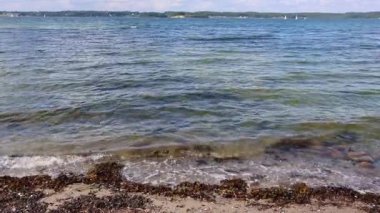 Yumuşak okyanus dalgalarının kumlu kıyı şeridini silip süpürüp yumuşak mavi su ve doğal deniz çevresi ile sakin deniz manzarası