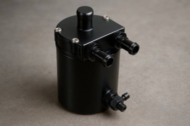 Silindirik siyah yağ tutacağı, gri bir yüzeyde duran konnektörlerle tasarımını ve işlevselliğini gözler önüne seriyor.