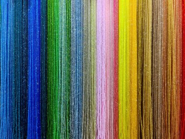 Vibrant bead strings hanging vertically, creating a rainbow spectrum with shimmering colors and texture