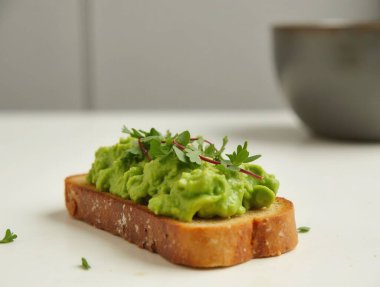 Taze yeşilliklerle süslenmiş sağlıklı avokado tostu besleyici ve görsel olarak çekici bir kahvaltı ya da atıştırmalık seçeneğini somutlaştırıyor.