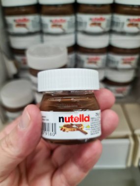 Hand holding a miniature Nutella chocolate hazelnut spread jar, showing brand and ingredients details
