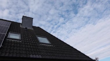 Modern solar panels installed on a residential house roof with black tiles. Sustainable and renewable energy technology concept for the home