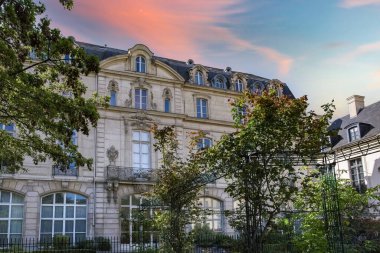 Paris, Saint-Gilles Meydanı, arka planda tipik binaları olan, üç katlı bir halk bahçesi.