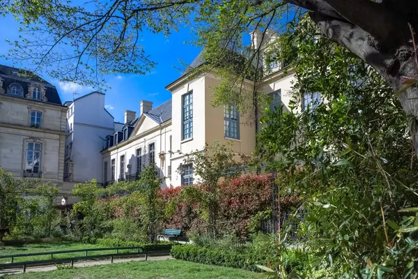Paris, Saint-Gilles Meydanı, arka planda tipik binaları olan, üç katlı bir halk bahçesi.