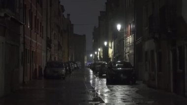 Street of the ancient city Chioggia at night, in the Venice lagoon, with parked cars. 