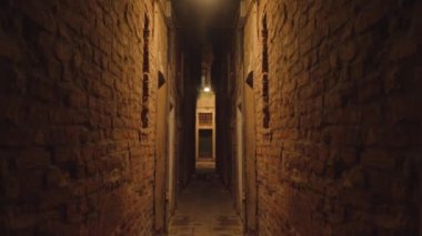 Narrow street at night between walls of brick buildings