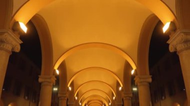  Under arcades on marble columns illuminated in the evening