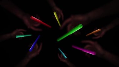 Colored markers thrown up in slow motion with hands on black background 