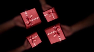 Four red gift boxes are thrown high from the hands. 