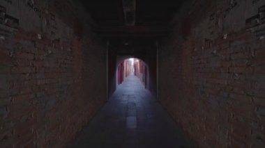 Forward movement under arcades between two walls of houses in the Venice lagoon