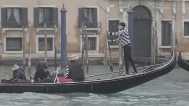 Venice, Italy - February 2023 - Gondolier in striped shirt carries tourists on gondola