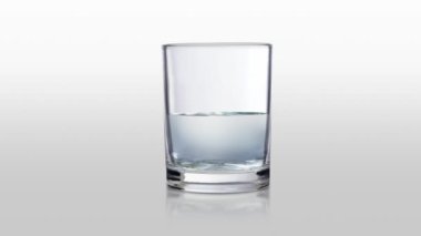 Cam beyaz zemin üzerinde durgun suyla doluyor.