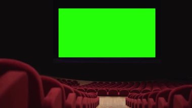 Boş kırmızı sandalyeli tiyatroda hiç insan yok. Ortasında büyük yeşil renkli bir ekran var..