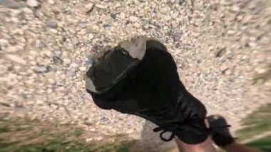 Toprak bir yolda ağır çekimde yürüyen bir adamın yürüyüş botlarıyla.