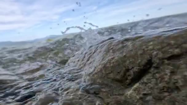 파도가 바위와 해변에서 파도에 튀어나오고 있습니다 — 비디오
