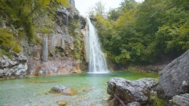 Yazın yeşil ağaçların arasındaki kayalıklardan çağlayan şelale.