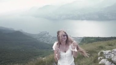 Mutlu genç kız Garda gölü dağlarında rüzgarda gülümsüyor.