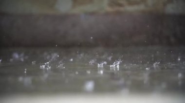 Yol yüzeyinin makro görüntüsü ağır çekimde sağanak yağışla doldurulmuş ve ıslanmış.