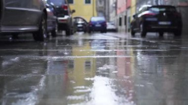 Şehirde park halindeki arabaların arasına yağmur yağıyor.