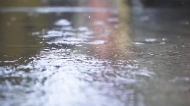 Yağmur, gündüz vakti su birikintisinin içine ağır çekimde düşer.