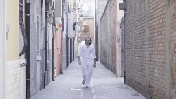 若い男 深刻な外観を持って 面白い方法で歩きます ヴェネツィアの通りに — ストック動画