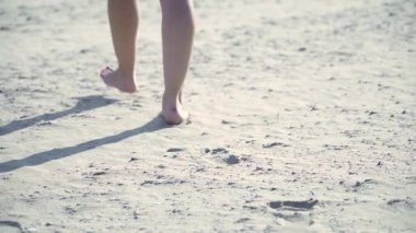 Bir kadının üzerinde yürüdüğü sıcak güneşin altında kum. Ayaklara yakın çekim..