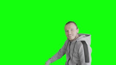 Sahnede bir adam belirir ve parmağını yeşil ekran ya da krom anahtarın boş kısmına doğrultur ve komik bir şekilde ortadan kaybolur..