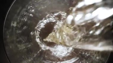 Ağır çekimde cam kadehe köpüklü şarap döküldü. Makro yukarıdan, camın içinde hareketlilik var..