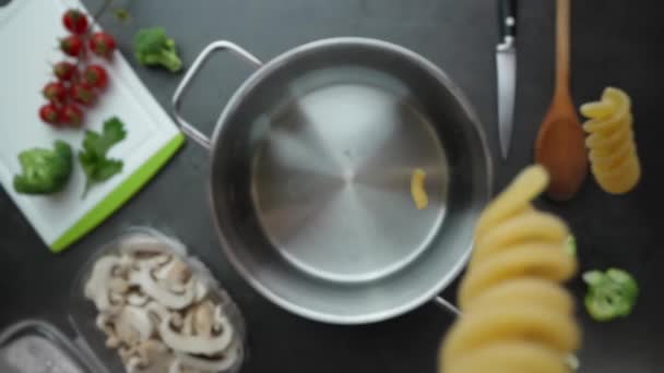 キッチンで水で鍋にカスケードするパスタのゆっくりとした動き 上からのマクロショット — ストック動画