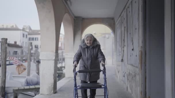 Äldre Kvinna Med Vandrare Promenader Längs Byggnader Hallen — Stockvideo