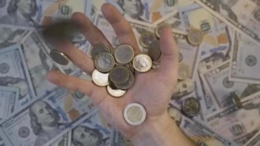 Avro paraları yukarıdan yavaş çekimde avucunun içine düşer. Arka planda Amerikan dolarlarını görebilirsiniz..