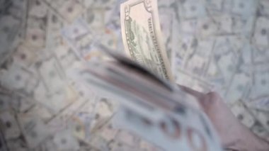 Dolarlar yavaş çekimde diğer bulanık banknotların üzerinde, eliyle yükselir..