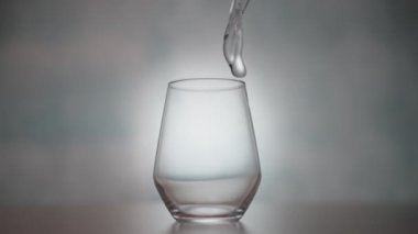 Doğal su yavaş çekimde cam bir şişenin içine düşer. Arka planda hafif bir etki yaratır. Güzel ve büyüleyici bir etki yaratır.. 