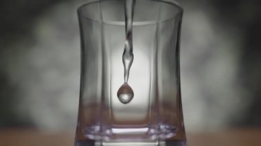 Yavaş çekimde makro çekim, cam bir şişeye düşerken suyu yakalar.. 