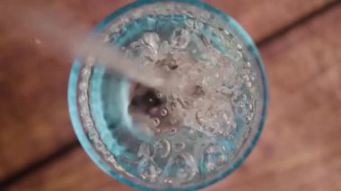 Yüksek açılı bir çekim, zaten dolu olan bardağa düşen suyu yakalar, taşkınlığı gösterir ve çarpmanın etkilerini gösterir.. 