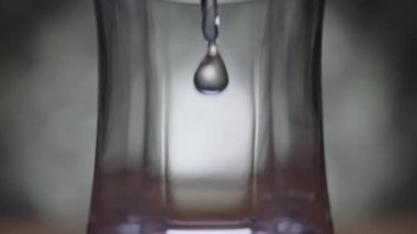 Bir makro görüntü, suyun yavaş çekimde cam bir şişeye düşüşünü yakalar ve su sıçratır.. 