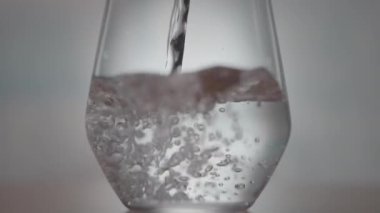 Su şeffaf bir bardağa dökülürken doluyor ve akan dereden kabarcıklar oluşturuyor.. 