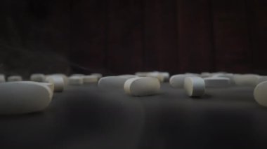 Yakın plan çekimde, karanlık bir yüzeye dağılmış beyaz haplar sağlık hizmetleri fikrini temsil ediyor.