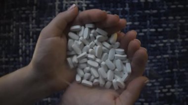 Beyaz tabletleri tutan ellerin detaylı görüntüsü. Sağlık ve ilaç temalarının resimlendirilmesi