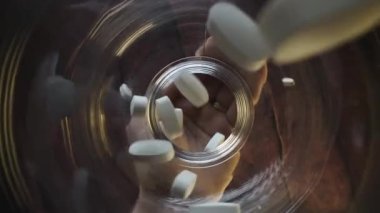 Görüntü ilaç kavanozuna uzanan bir eli gösteriyor. Tedavi amaçlı ilaç alma eylemini vurguluyor.