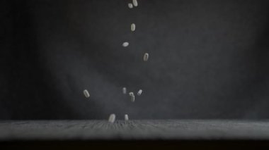 Yakından çekilen görüntü, düşen kapsülleri, hareket ve yerçekimi kavramlarını gösteren karanlık bir arkaplan üzerinde yakalar.