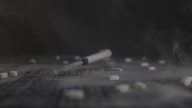 Karanlık bir arka plandaki şırınga ve haplar bağımlılığı ve madde bağımlılığını simgeler, sağlık krizini yansıtır