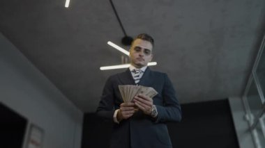 Kendine güvenen ve başarılı bir iş adamı, şık ve modern ofis ortamında nakit parayı verimli bir şekilde idare ediyor.