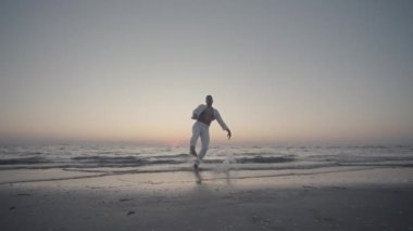 Beyazlar içindeki balerin yavaşça denize atlar.