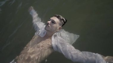 Gıcır gıcır beyaz gömlekli bir adam, zarif bir şekilde su yüzeyinde süzülüyor, sükunet duygusunu somutlaştırıyor.