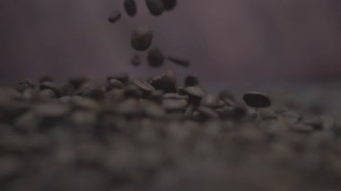 Kahve çekirdeğinin dinamik ve büyüleyici görüntüsü zarif bir şekilde koyu, zengin bir yüzeye dökülüyor.