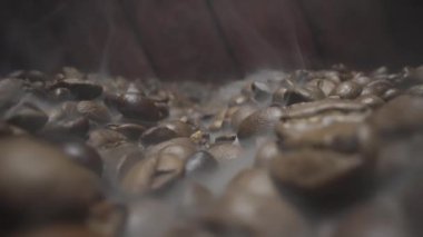Kızartma işlemi bittikten sonra buhar saçan zengin, aromatik kahve çekirdeklerinin yakın çekim görüntüsü.