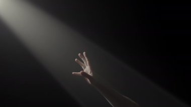 Karanlığın ortasında ışık saçan bir ışığa doğru uzanan bir el, umut ve arzuyu simgeliyor.